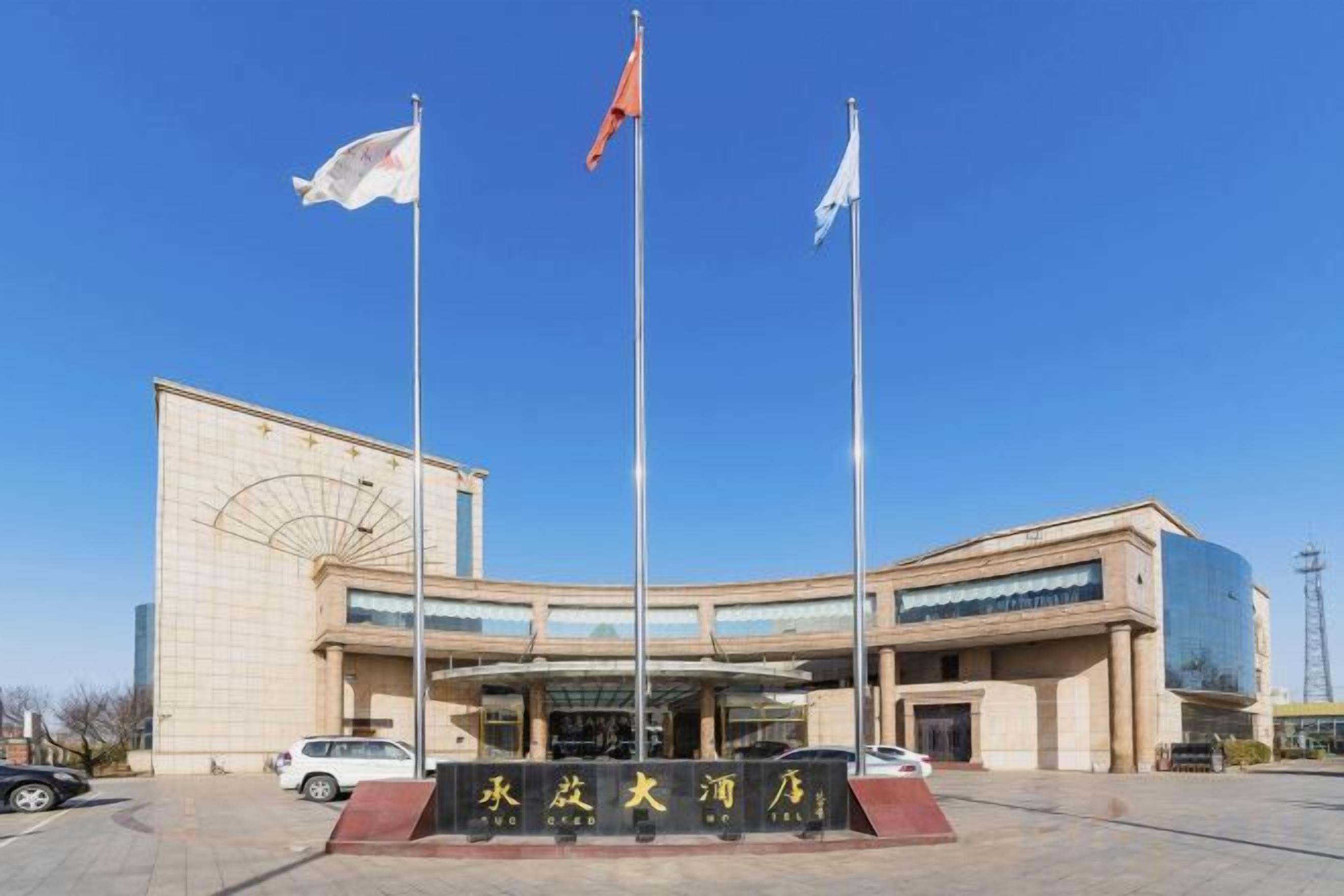 Un edificio con una entrada amplia, varias banderas y un letrero con caracteres chinos.