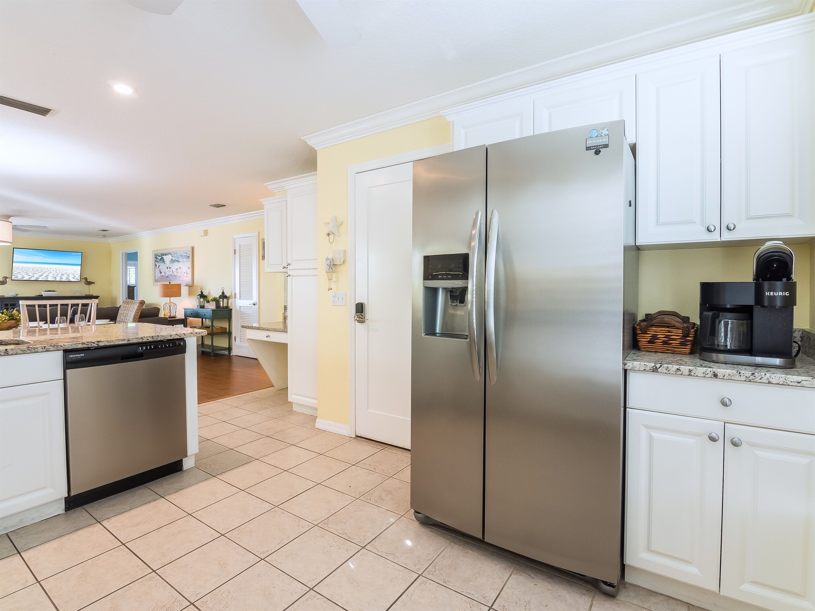 A modern kitchen with a stainless steel refrigerator, a built-in water dispenser, and a coffee maker on the countertop.