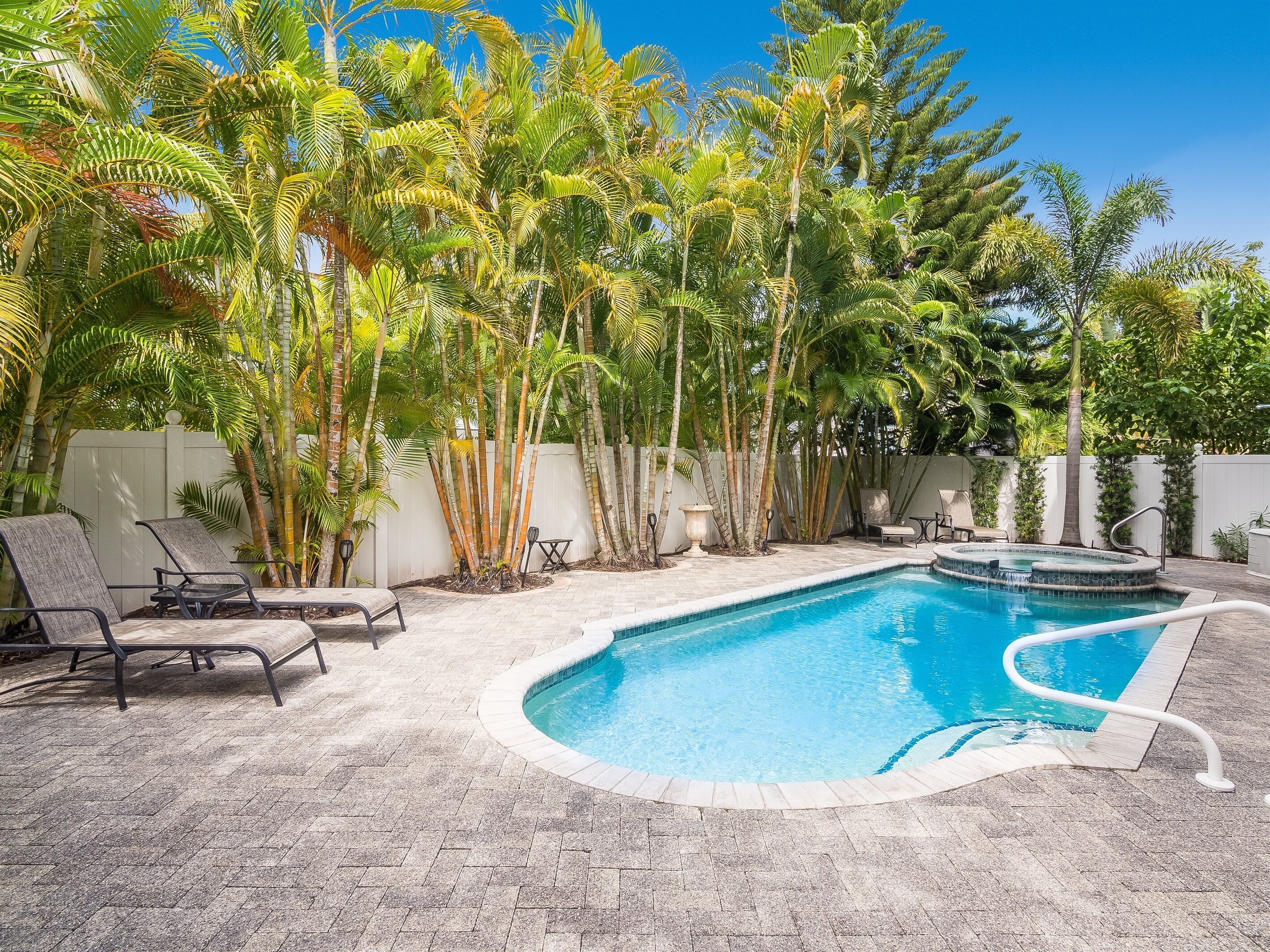 A swimming pool surrounded by palm trees and lounge chairs.