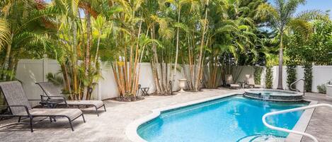 A swimming pool surrounded by palm trees and lounge chairs.