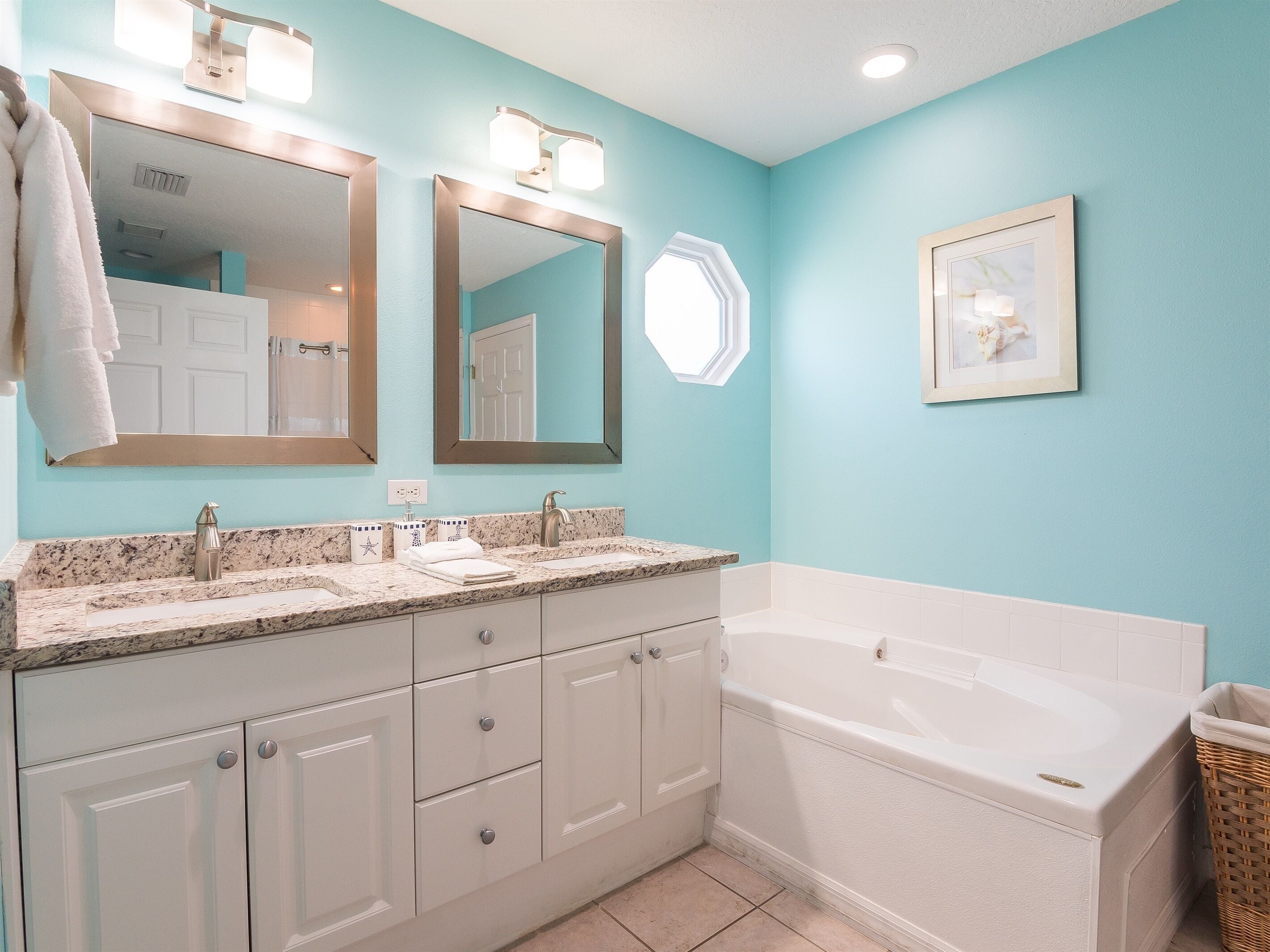 Une salle de bain avec deux lavabos, une grande baignoire et un tableau encadré au mur.