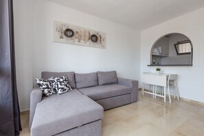 A modern living room with a grey sectional sofa, a white desk, and a large mirror.