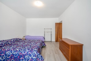 A bedroom with a bed, a wooden dresser, and a wardrobe.