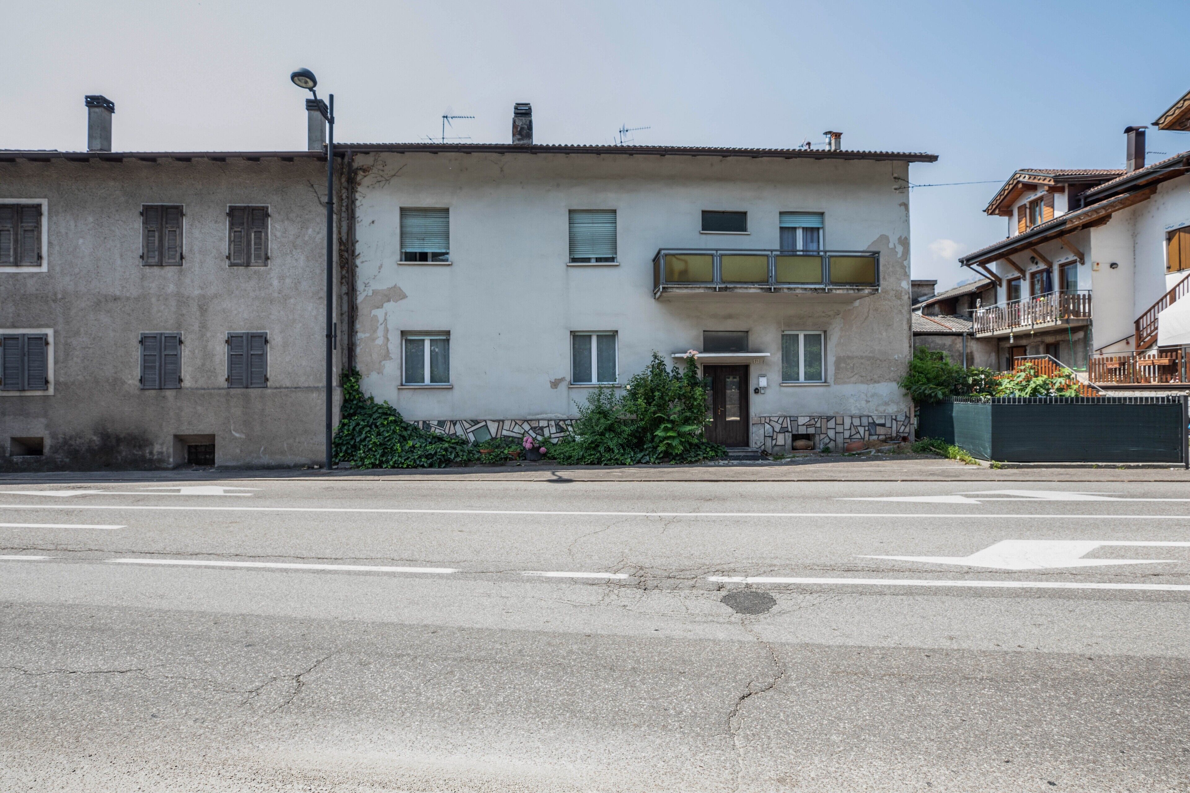 Ein mehrgeschossiges Gebäude mit Balkon, Tür und kleinem Garten.
