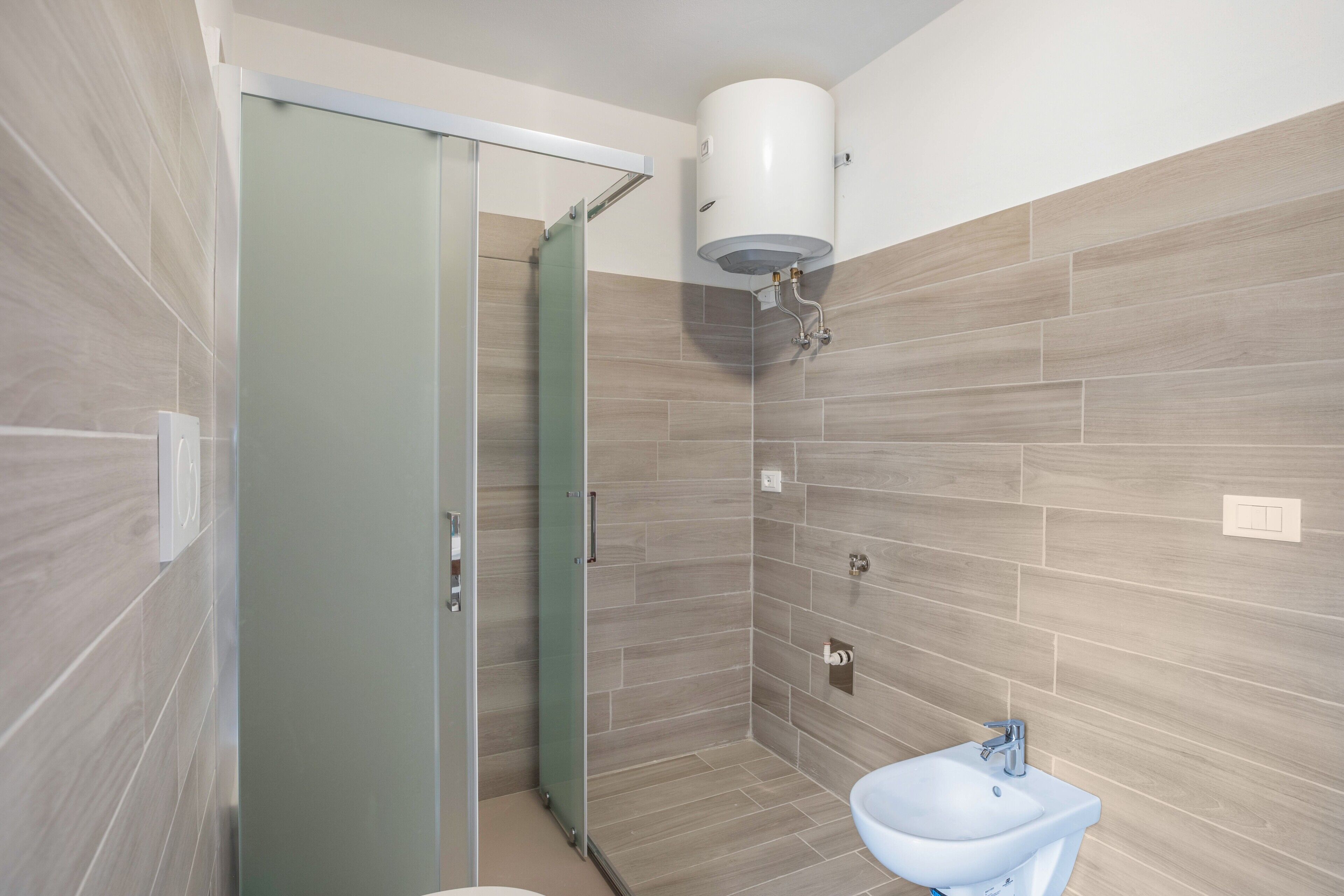 A modern bathroom with a glass shower door, a white sink, and a toilet.