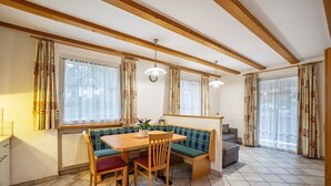 A dining area with a wooden table, bench seating, and a radiator. - Pet-Friendly Holiday Apartment 'Kuenz Dolomiten Drau' with Mountain View (San Candido)