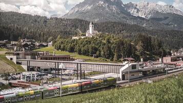 Ein Bahnhof mit einer Brücke, einer Kirche und Bergen im Hintergrund.