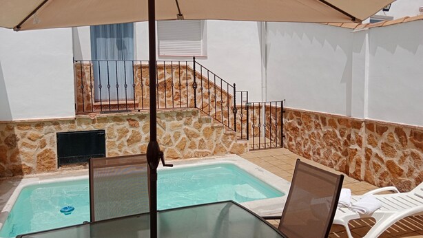 A pool area with a glass table and chairs, a covered umbrella, and a stone wall. - Holiday Home La Reconquista with Pool, Garden & Wi-Fi (Santa Elena)