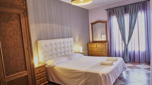 A bedroom with a large bed, wooden wardrobe, a dresser, a mirror, and a window with curtains. - Holiday Home La Reconquista with Pool, Garden & Wi-Fi (Santa Elena)