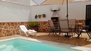A swimming pool with lounge chairs and a barbecue area. - Holiday Home La Reconquista with Pool, Garden & Wi-Fi (Santa Elena)