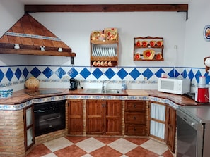 Une cuisine avec un carrelage à motifs, des placards en bois, un évier, un four à micro-ondes et une machine à café.