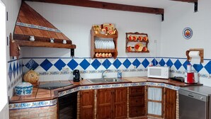 A kitchen with a checkered floor, wooden cabinets, a brick oven, a microwave, and a coffee machine. - Holiday Home La Reconquista with Pool, Garden & Wi-Fi (Santa Elena)