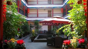 A multi-level atrium with potted plants, a central seating area, and a staircase leading to upper floors.