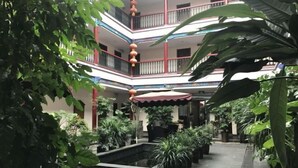 A multi-level atrium with a central water feature, surrounded by potted plants and a red awning. - Qincaige Hostel (Chongqing)