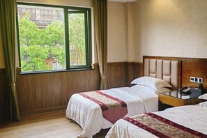 A hotel room with two beds, a wooden headboard, a nightstand, and a window with curtains. - Qincaige Hostel (Chongqing)