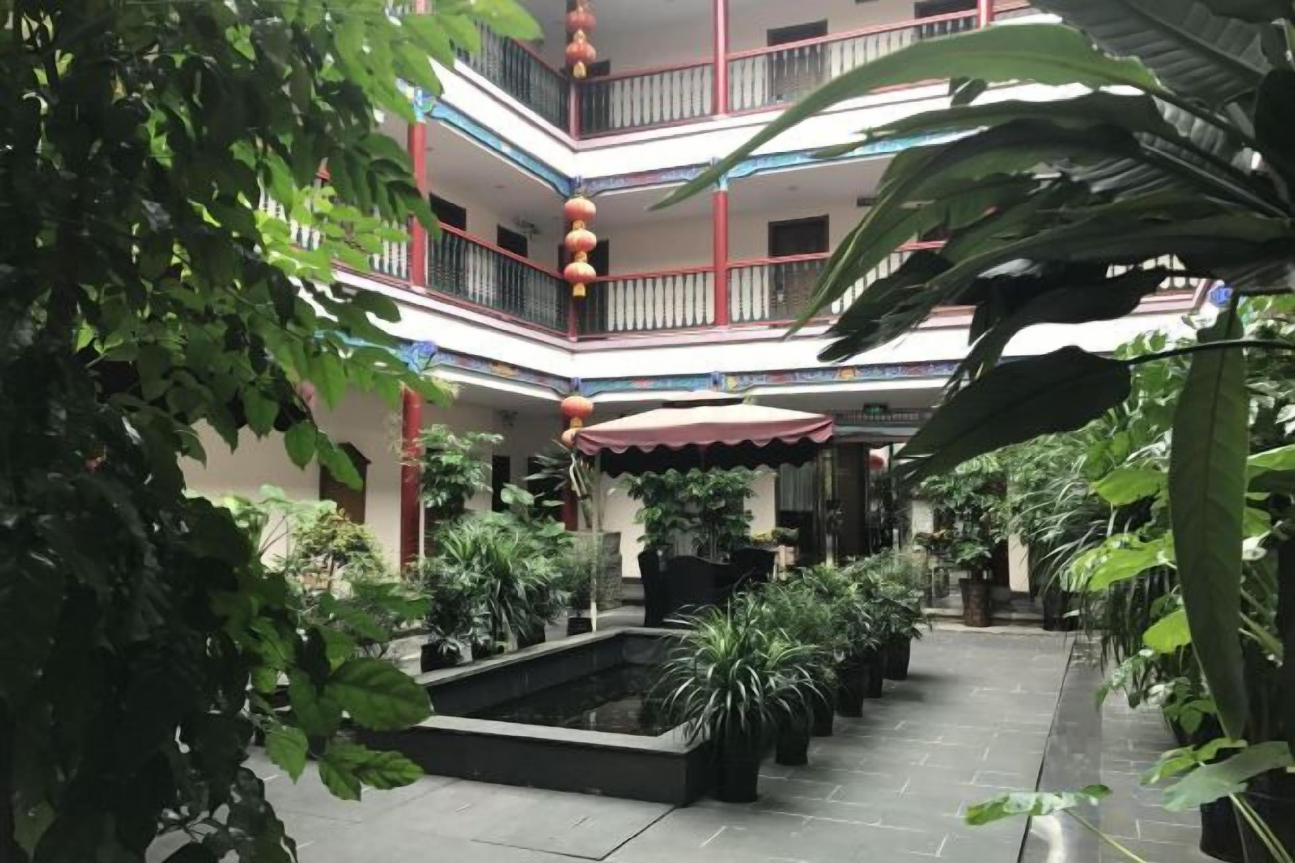 Ein mehrgeschossiges Atrium mit Topfpflanzen, einer Wasserattraktion in der Mitte und einem roten Laternen.