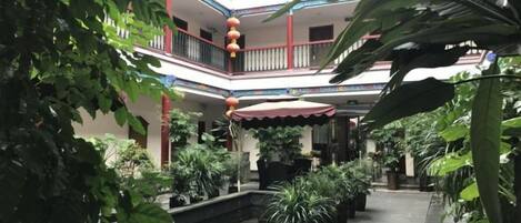 Ein mehrgeschossiges Atrium mit Topfpflanzen, einer Wasserattraktion in der Mitte und einem roten Laternen.