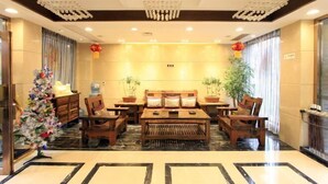 A lobby with a reception desk, seating area, and decorative plants. - Qincaige Hostel (Chongqing)