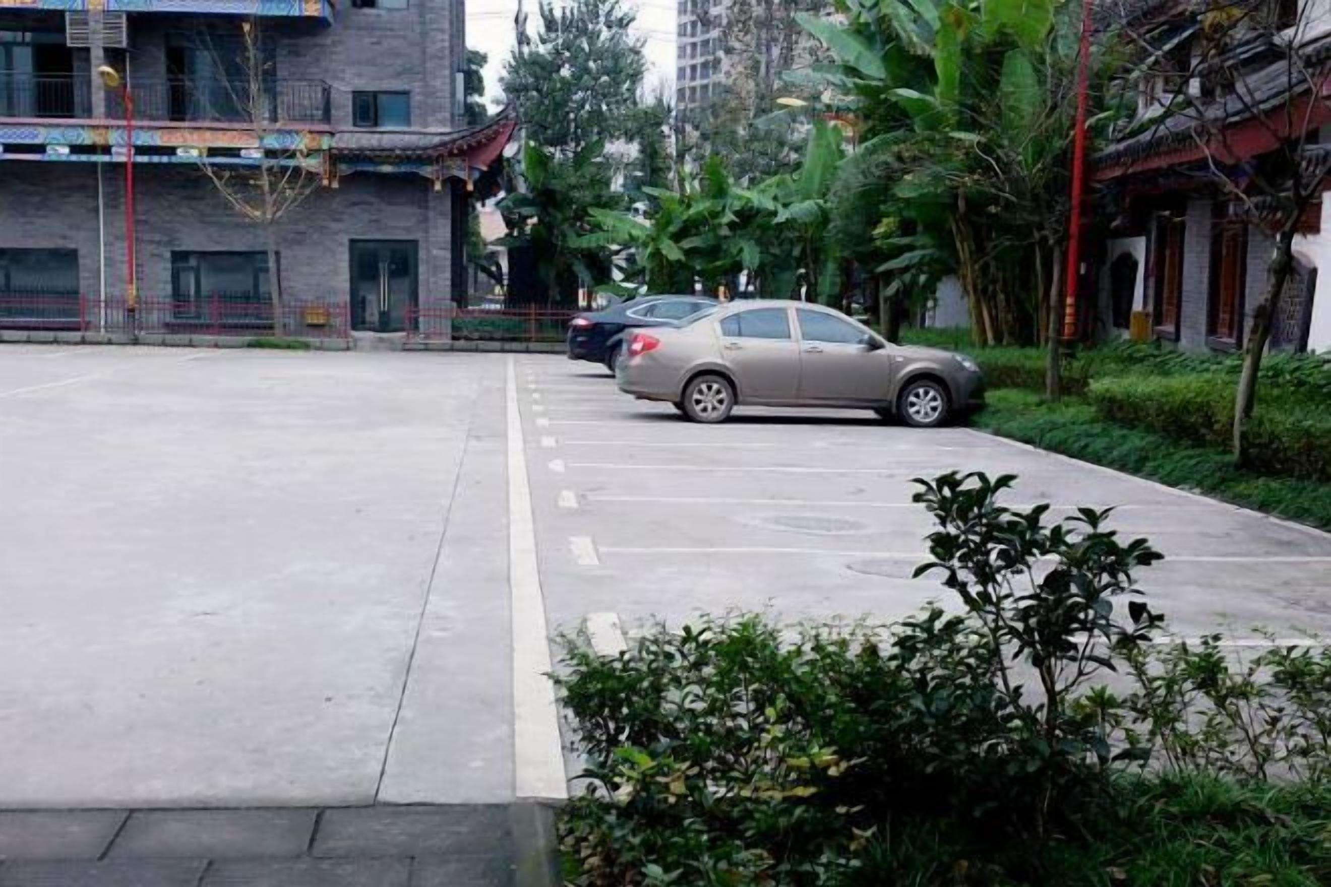A parking lot with two cars, surrounded by buildings and greenery.