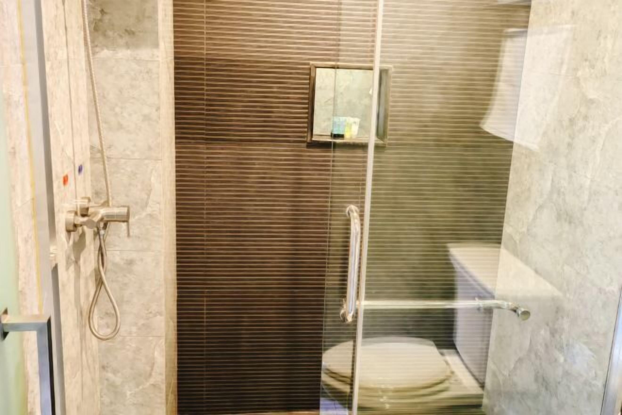 A glass-enclosed shower stall with a toilet and a small window.