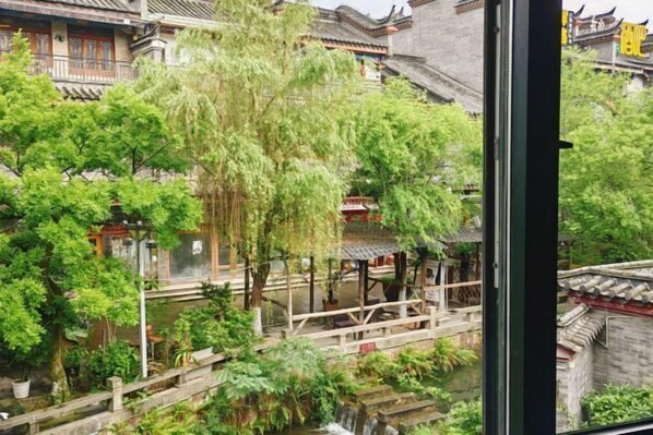 Un patio tradicional con un puente de madera, rodeado de abundante vegetación y arquitectura típica.