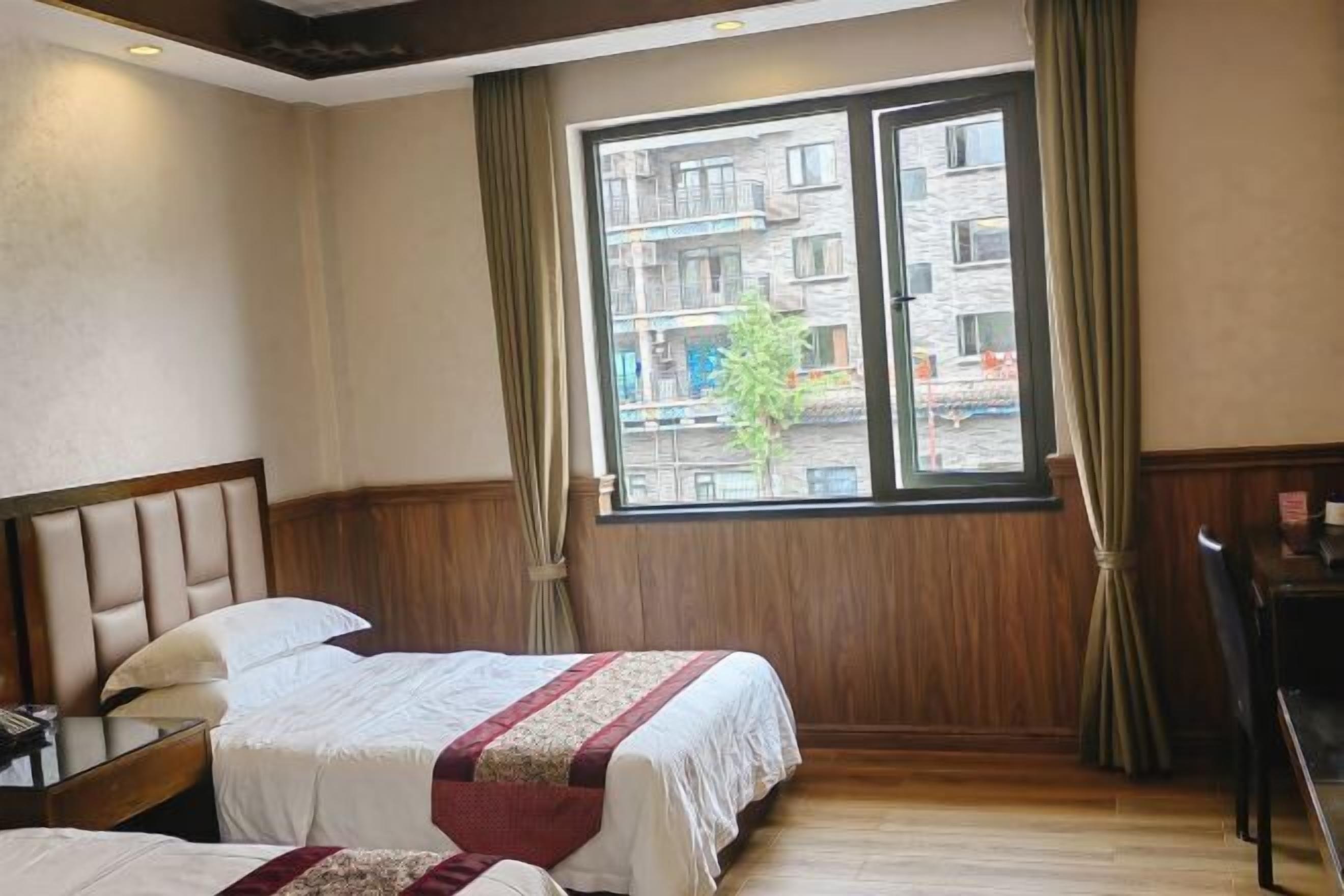 A hotel room with a bed, a nightstand, a desk, and a window with curtains.