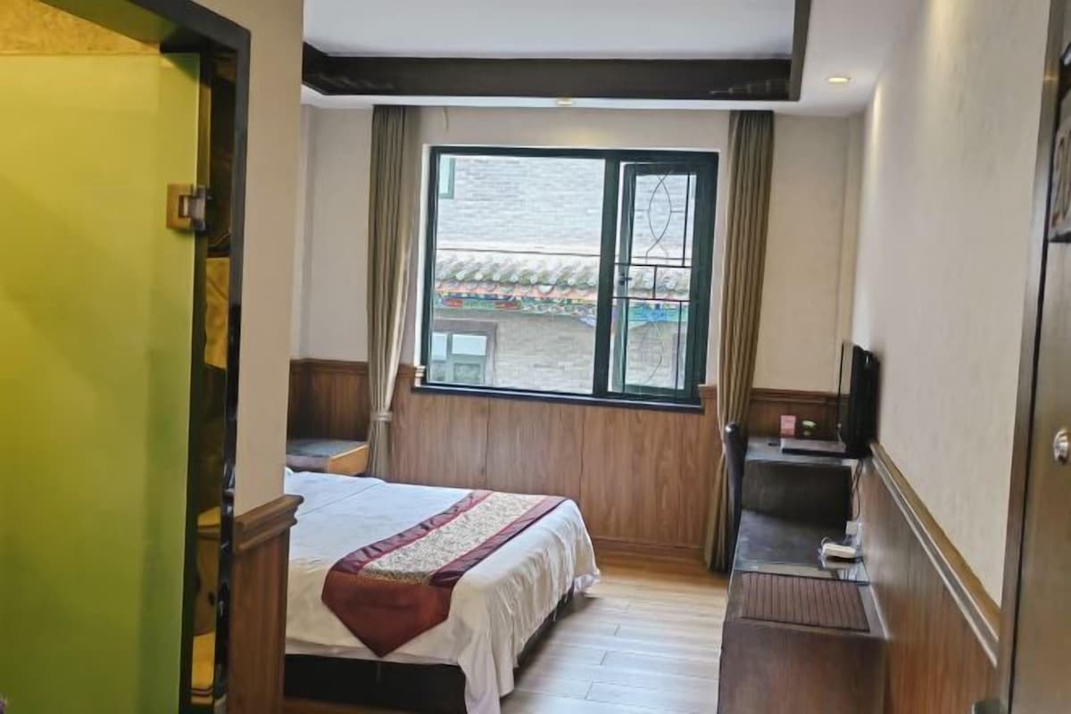 Habitación de hotel con cama, escritorio y ventana con vista a un edificio tradicional.