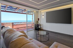 Una sala de estar moderna con un sofá, una mesa de centro de cristal y una pantalla de televisión grande.