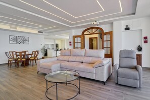 Una sala moderna con un sofá modular, una mesa de centro de vidrio y un sillón gris.