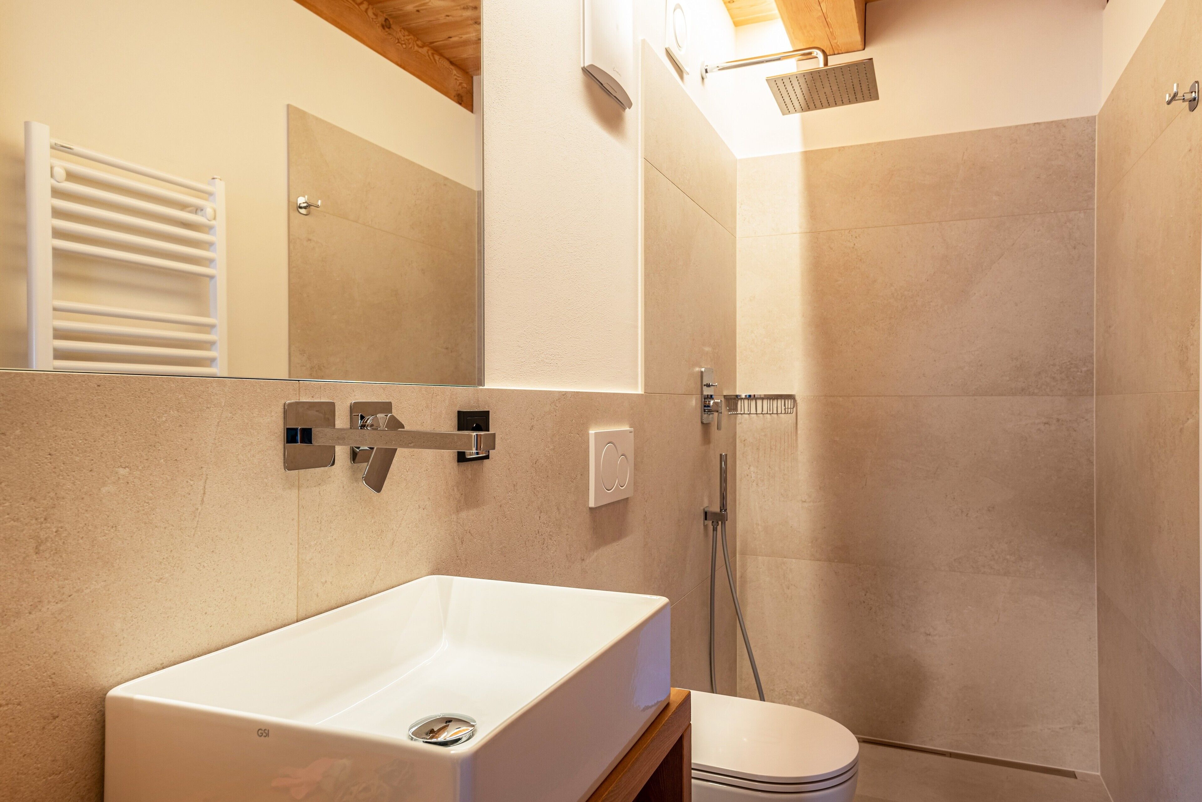 A modern bathroom with a white sink, a toilet, a shower, and a mirror.