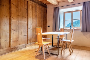 Un intérieur en bois avec une table et des chaises, une fenêtre donnant sur une montagne et un mur en bois.