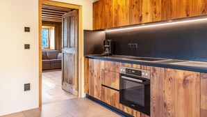 A modern kitchen with wooden cabinetry, a built-in oven, and a coffee maker. - Holiday Apartment Egger an der Lahn - Nonno with Mountain View, Terrace and Wi-Fi (San Genesio)
