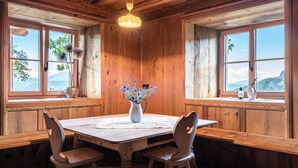 A wooden dining room with a table, chairs, and a vase of flowers. - Holiday Apartment Egger an der Lahn - Nonno with Mountain View, Terrace and Wi-Fi (San Genesio)