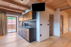 Une cuisine moderne avec des meubles en bois, une cuisinière encastrée et un téléviseur à écran plat fixé au mur.