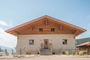 Une maison en bois à deux étages, avec un toit en pente, une porte d’entrée et un escalier menant à l’entrée.
