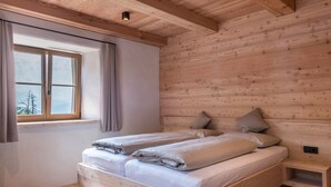 Una habitación tipo cabaña de madera con una cama, una ventana y una mesita de noche integrada.