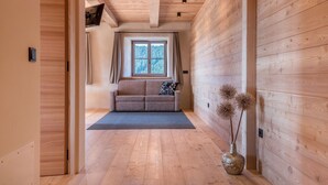 Un interior de madera con un sofá, una ventana y un jarrón con flores secas.