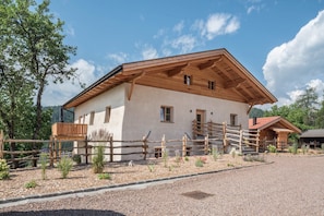A wooden building with a sloped roof, a gravel driveway, and a wooden fence.