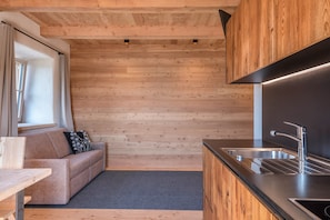 Une cuisine moderne avec des murs en bois, un canapé agrémenté d’un coussin noir et blanc, et une fenêtre avec des rideaux.