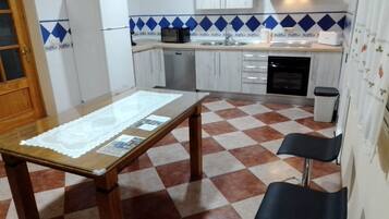 A kitchen with a checkered floor, a table with a lace tablecloth, and a microwave.