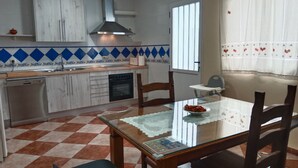 Cocina compacta con lavavajillas, horno y comedor con mesa y sillas.