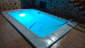 Una piscina con un muro de piedra y una barandilla metálica.