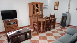 Una sala de estar con televisor, aparador de madera, mesa de comedor, sillas y sofá.