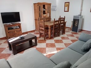 A living room with a TV, wooden cabinet, dining table, chairs, and a sofa. - Holiday Home Nuevas Poblaciones with Mountain View, Pool & Wi-Fi (Santa elena)