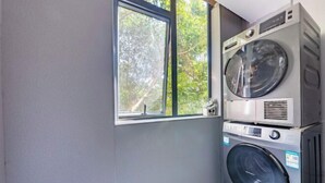 A laundry room with two stacked washing machines and a window providing natural light. - Shankee Chain Hotel (Zhuhai Jing'an Bridge) (Zhuhai)
