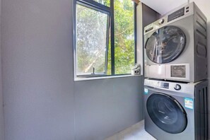 A laundry room with stacked washing machines and a window.