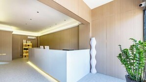 A modern reception desk with a minimalist design, a potted plant, and a clean, well-lit interior. - Shankee Chain Hotel (Zhuhai Jing'an Bridge) (Zhuhai)