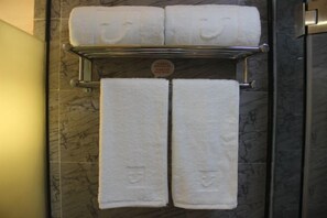A bathroom with a towel rack holding three white towels and a sign with red text. - Shankee Chain Hotel (Zhuhai Jing'an Bridge) (Zhuhai)