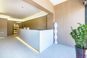 A reception area with a white reception desk, a potted plant, and a modern interior design. - Shankee Chain Hotel (Zhuhai Jing'an Bridge) (Zhuhai)