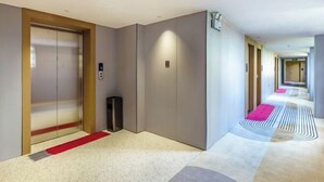 A modern hotel corridor with a red carpet, a trash bin, and a patterned floor. - Shankee Chain Hotel (Zhuhai Jing'an Bridge) (Zhuhai)
